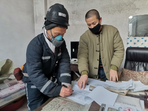 兴安矿动力科排水队井下水泵司机朱甲民（图左）在安全确认本上签字