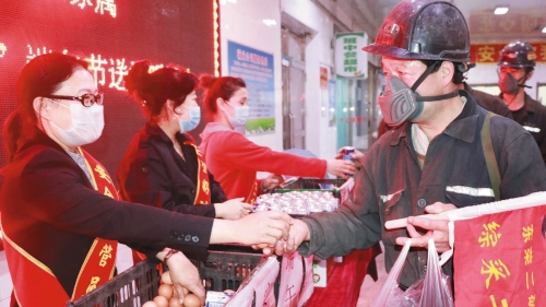 图为：东荣二矿女工将鸡蛋和牛奶递到职工手中，叮嘱“安全第一”。